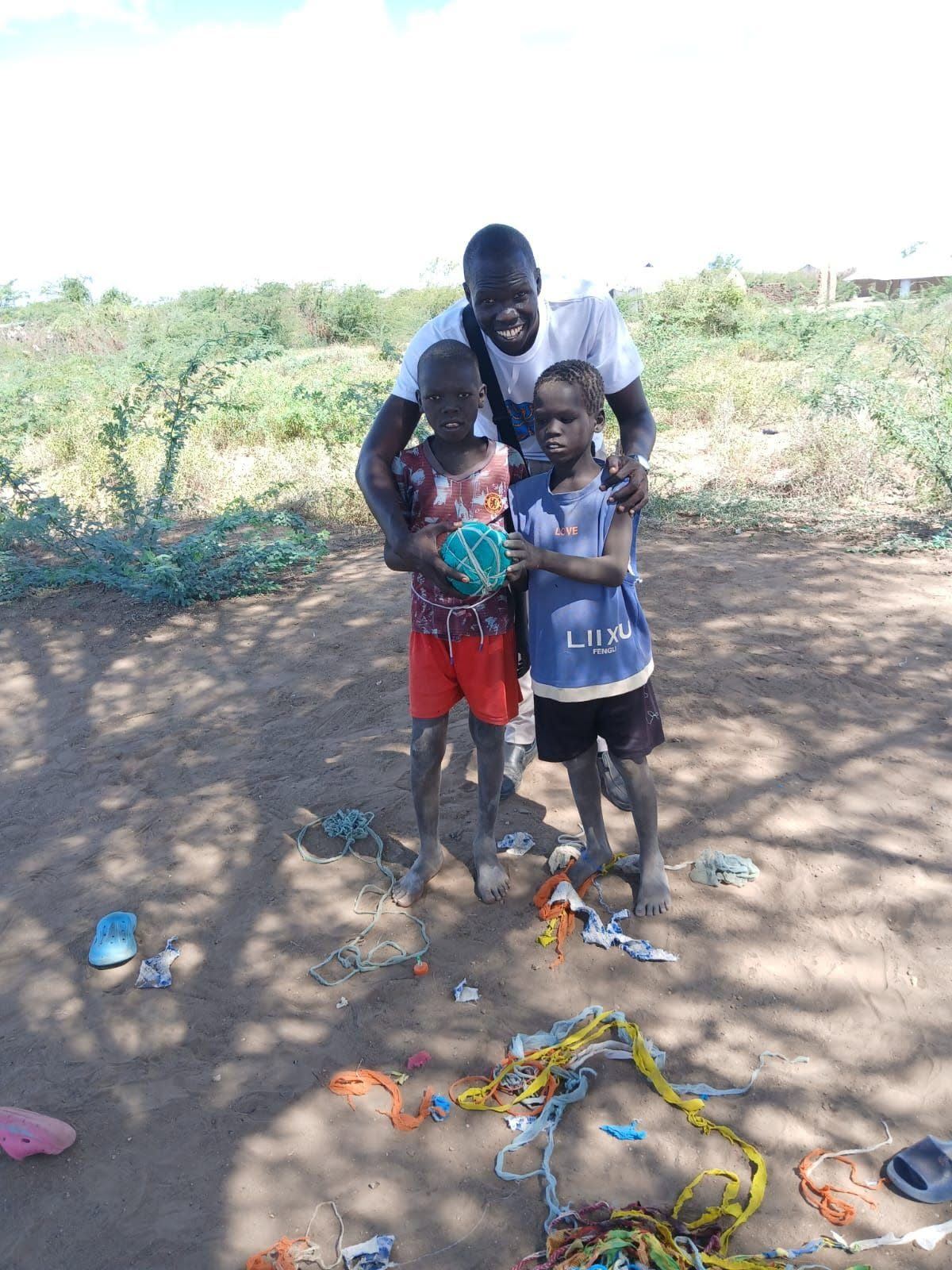 a coach with two young footballers holding a ball